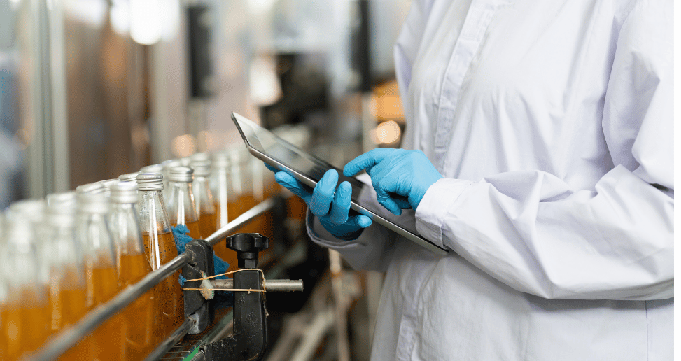 Les mains d'un travailleur travaillent avec une tablette numérique pour vérifier le système de gestion des informations de laboratoire STARLIMS dans une usine de boissons